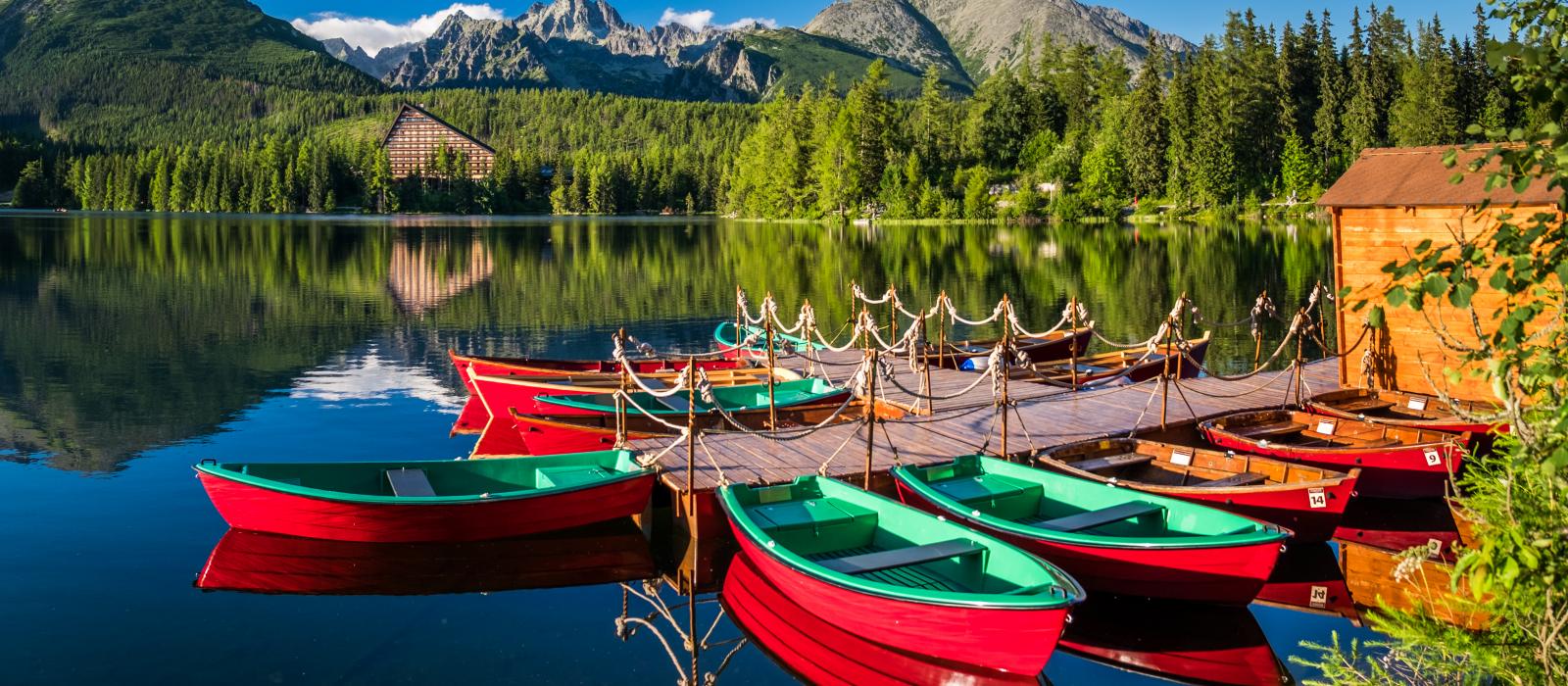 red row boats at dock on calm lake surrounded by green hills